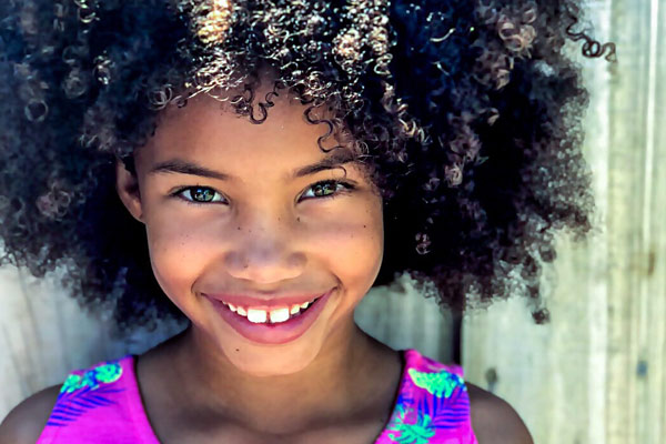 Young African-American girl with curly hair smiling.