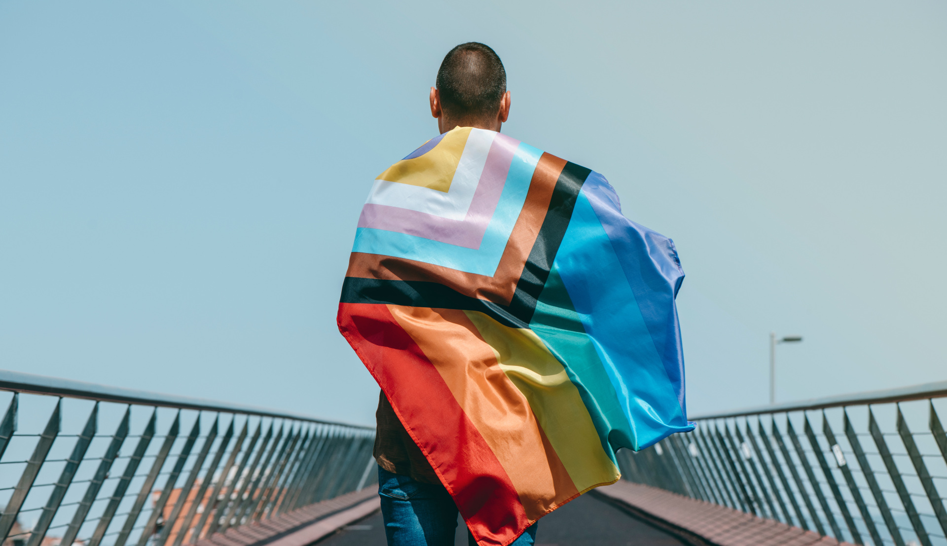 person with pride flag draped over their back.