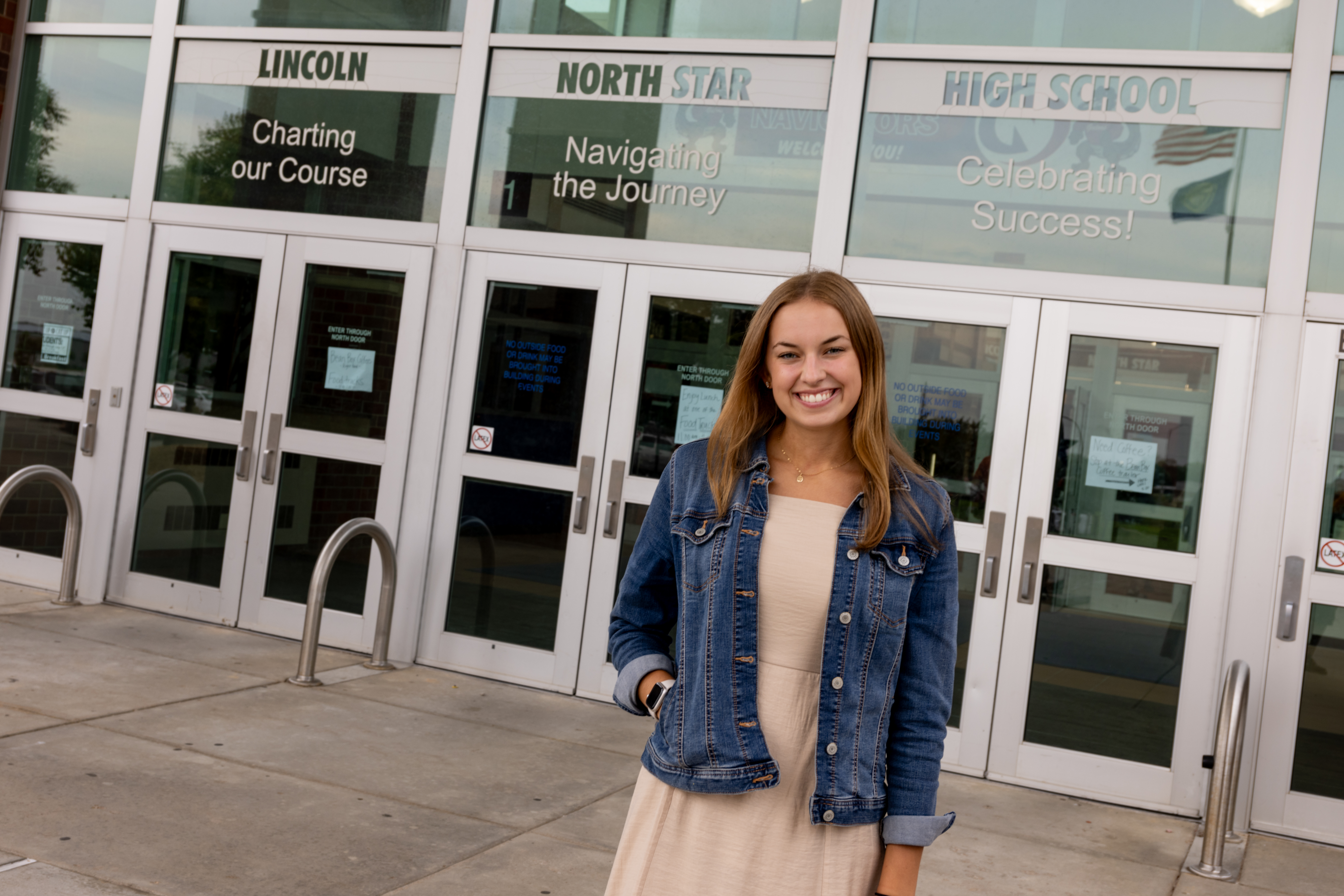 Sydney Gubbels stands outside of the glass door entrance to Lincoln North Star High School. 