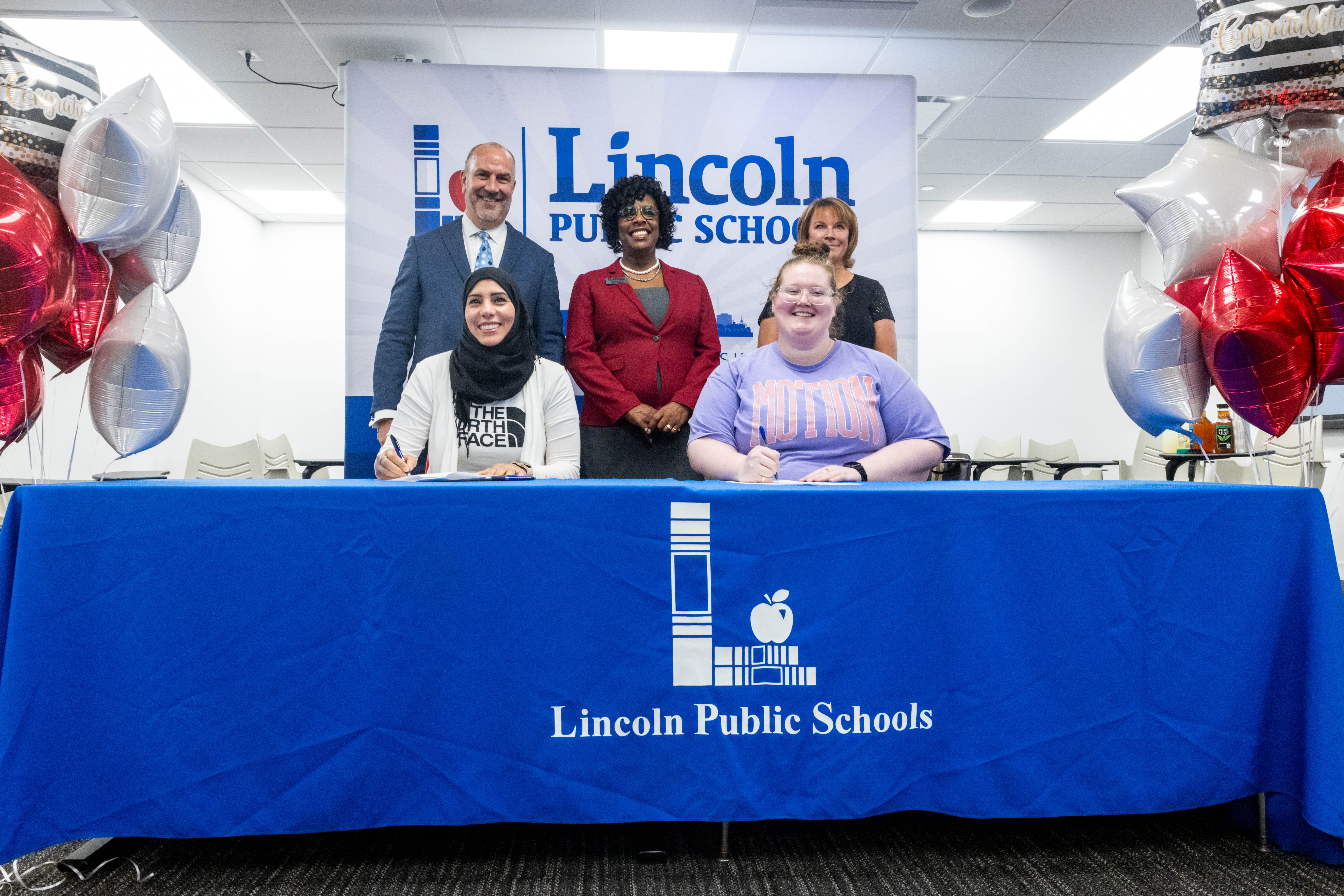 Dr. Paul Gausman (back row, left), Dr. Vann Price and Dr. Sue Kemp look on as two paraeducators sign their agreements to participate in the first cohort of the Para Pathway to Teaching pilot program.