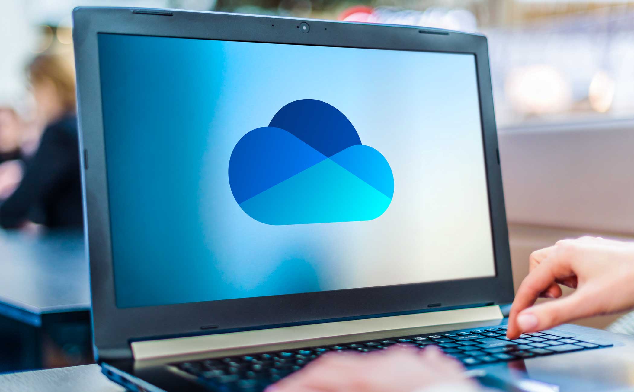 Laptop sitting on a table. The screen depicts a blue cloud graphic. 