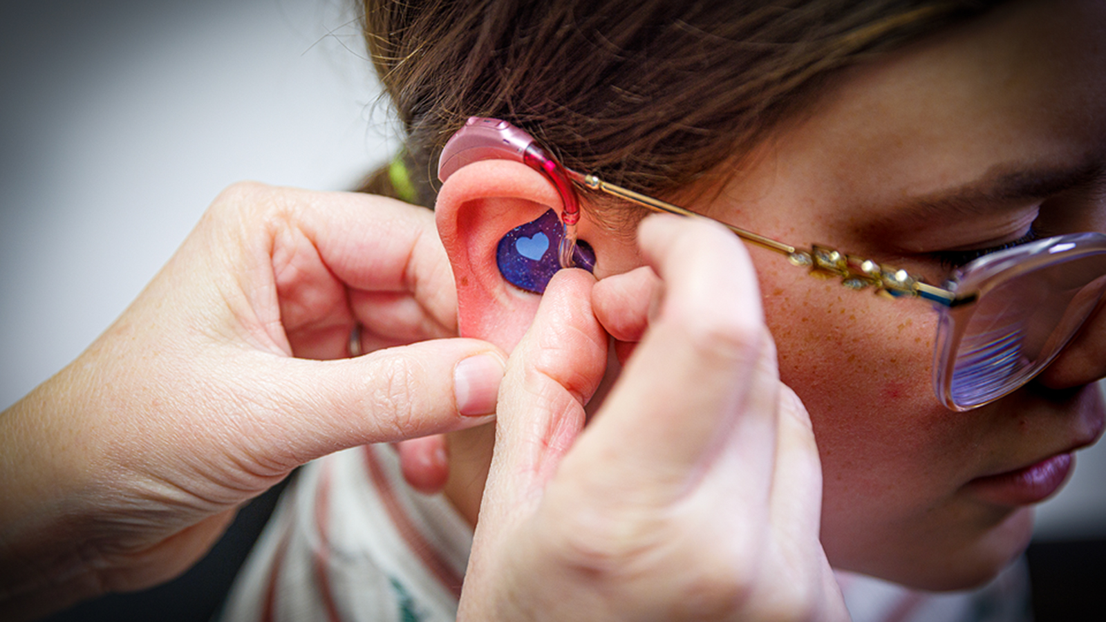Audiologist Stacie Ray checks the ears and hearing aids of 13-year-old Chloie Lechance.