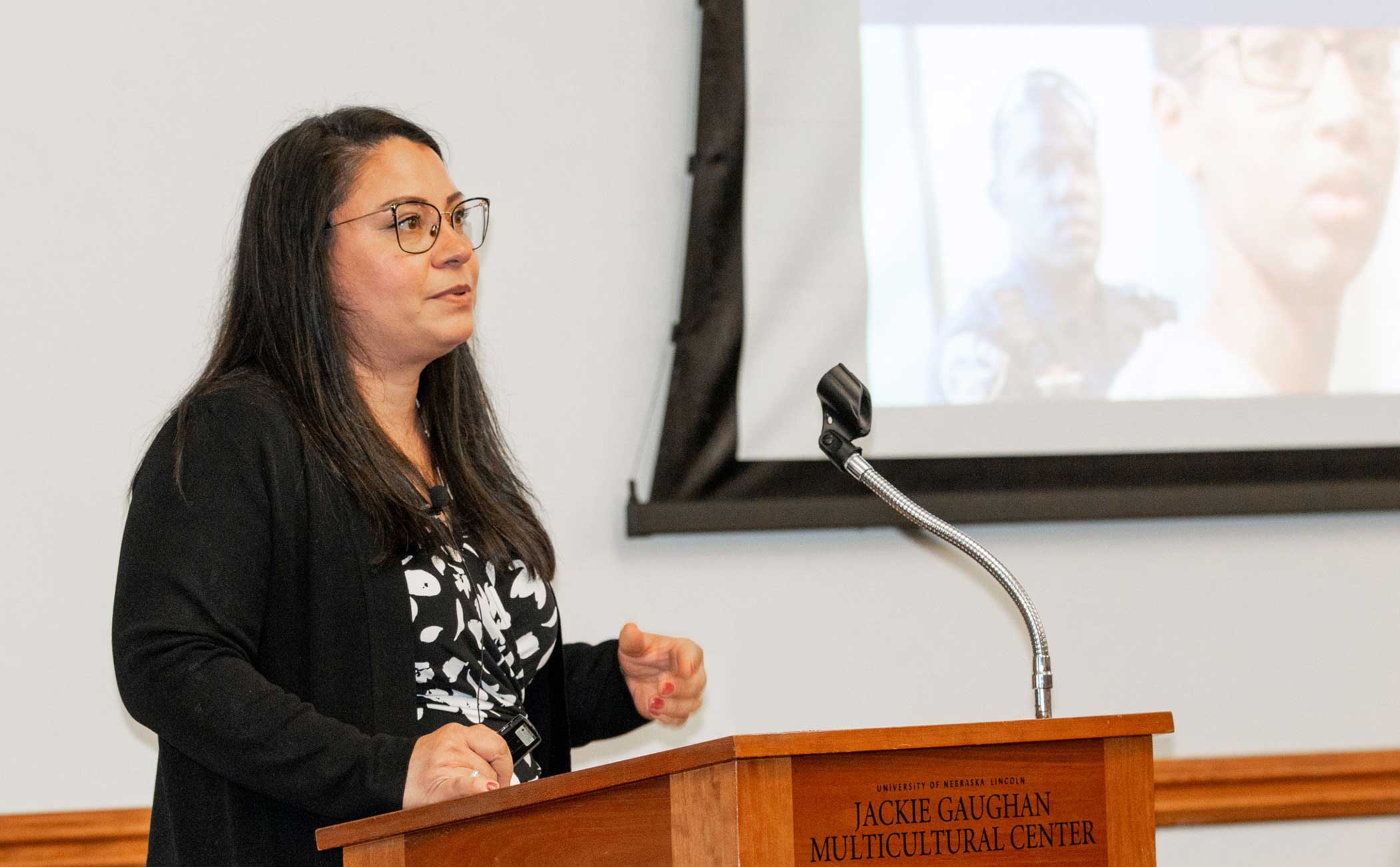 Deborah Rivas-Drake presents at a wooden podium in the Jackie Gaughn Multicultural Center. 