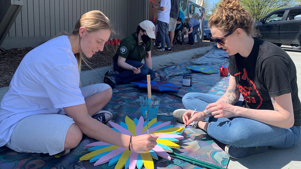 Peace Corps Prep students Kenzie Steiner and Katie Schmitz paint a mural during a group volunteer opportunity at the LUX Center for the Arts in May 2022.