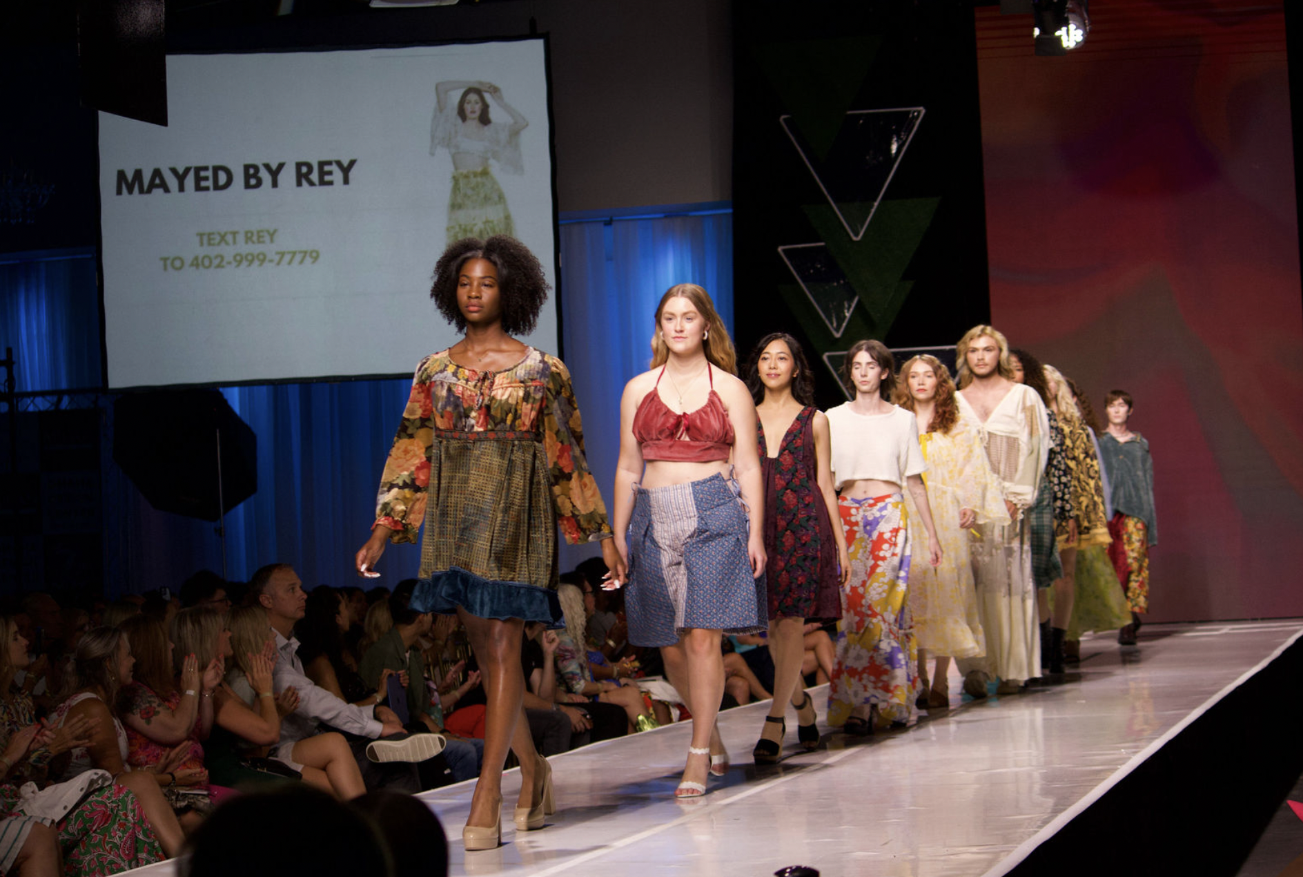 6+ individuals wearing handmade looks by ReyAnna Moore walk the runway at Omaha Fashion Week. 