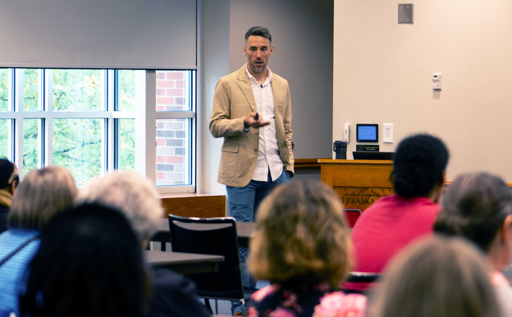 Scott Frohn holds a presentation clicker and speaks to a full room in the Nebraska Union. 