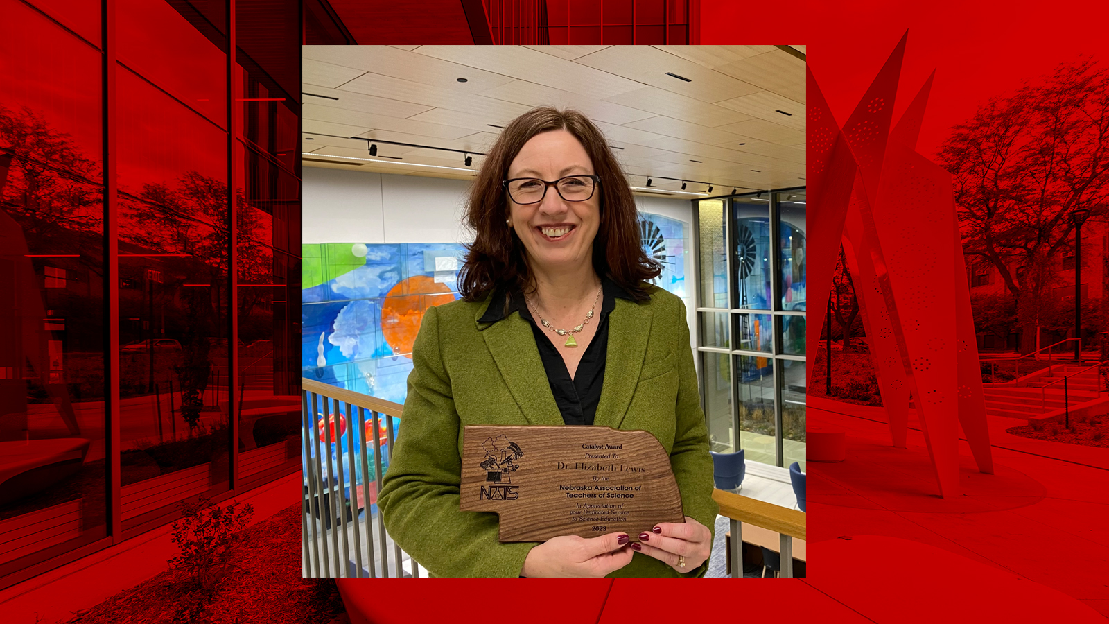 Beth Lewis smiles with her Catalyst Award in Carolyn Pope Edwards Hall. Exterior photo of CPEH with red overlay in background.