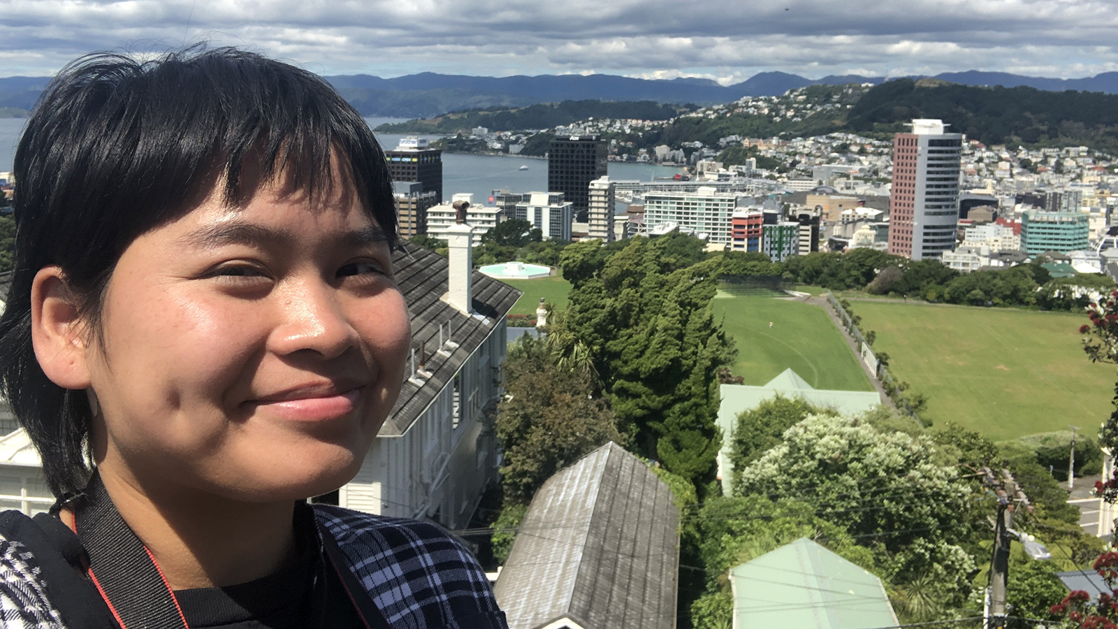 Lay Wah smiles for a selfie above a city in the background