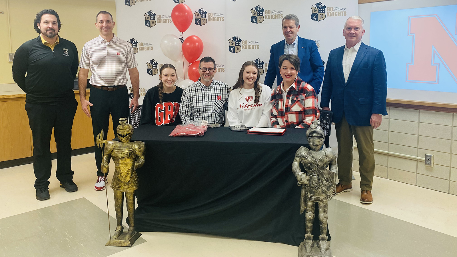Lillias McKillip is joined at the signing day at Lincoln Southeast High School by her sister Bea, parents Austin and Jessica, Southeast Principal Tanner Penrod, Gov. Jim Pillen, University of Nebraska Interim President Chris Kabourek, and Regent Tim Clare of Lincoln
