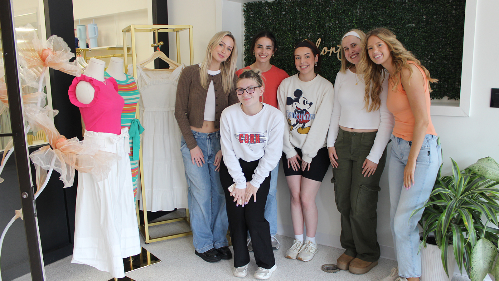 six TMFD students pose for a group photos next to the window display they created at House of Colour