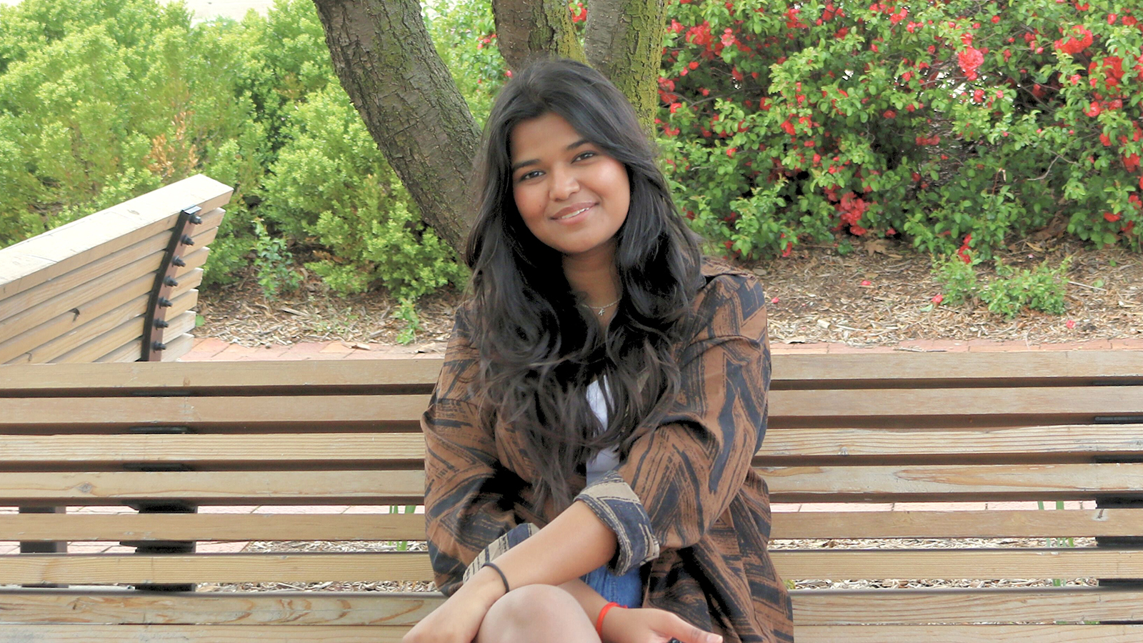 Diya Rana sits on a bench outside under a tree