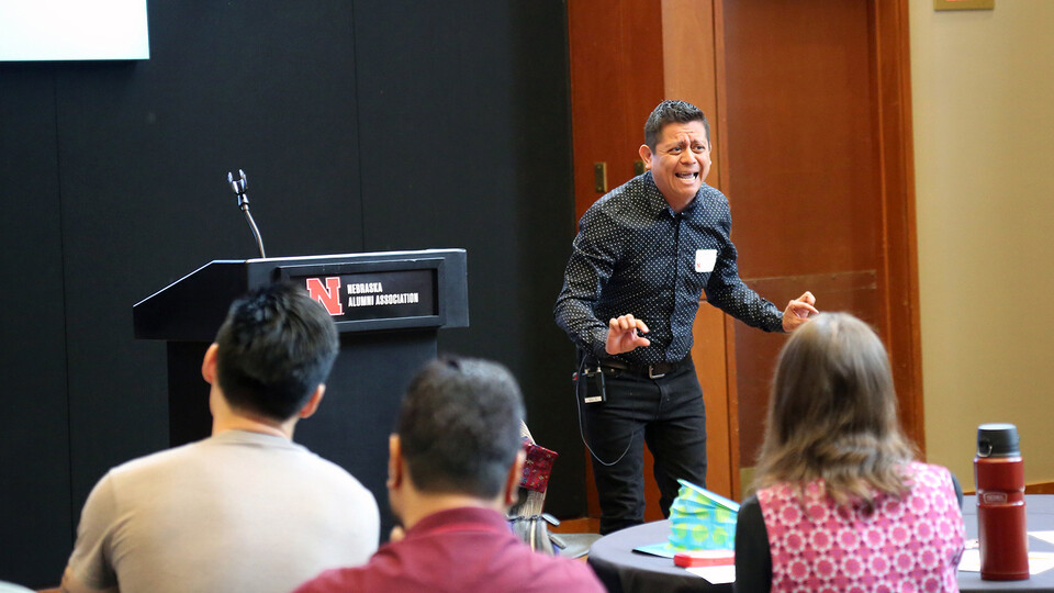 Héctor Palala presents at the front of the room near a podium during the Student Research Slam. 