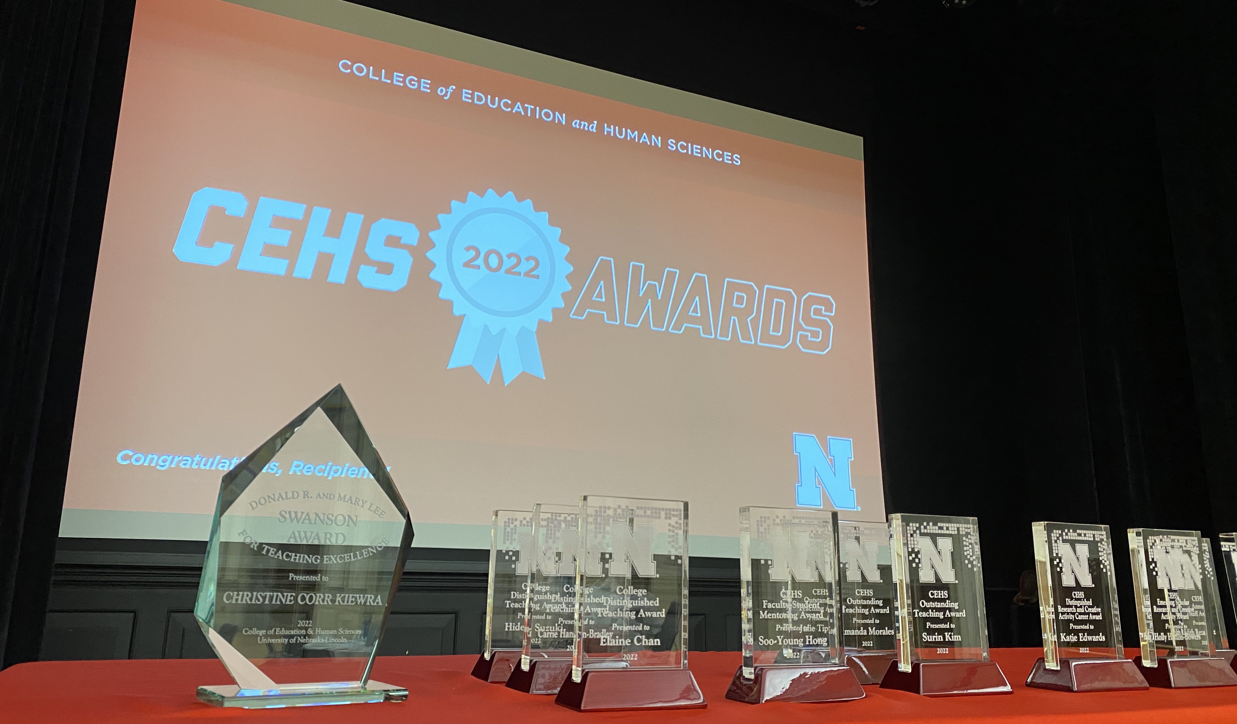 Several glass awards in front of a large red screen. 