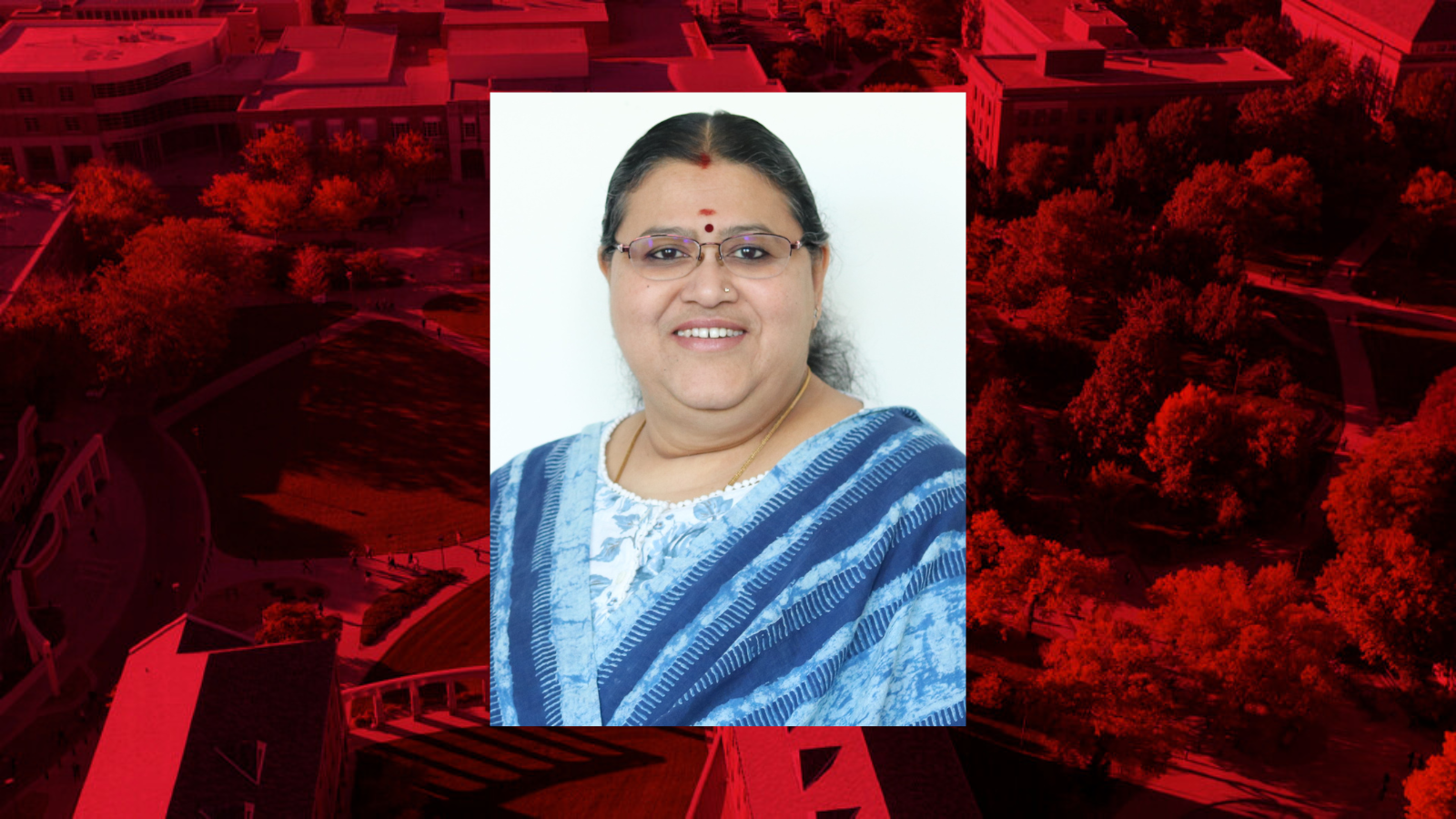 Professional headshot of Uma Ganesan on a red background.