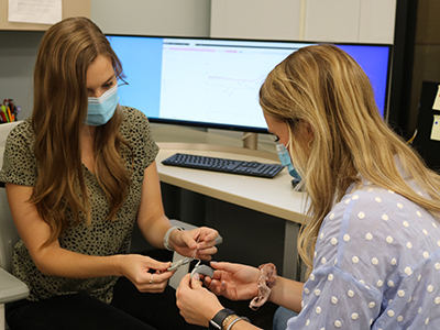 two Husker AuD students examine a cochlear implant while conducting research at the Cochlear Implant Research Lab
