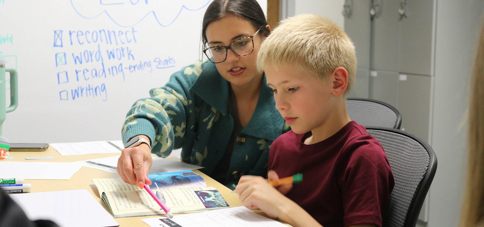 A Husker student explains a reading comprehension activity to a young boy during a tutoring session at the Schmoker Reading Center.