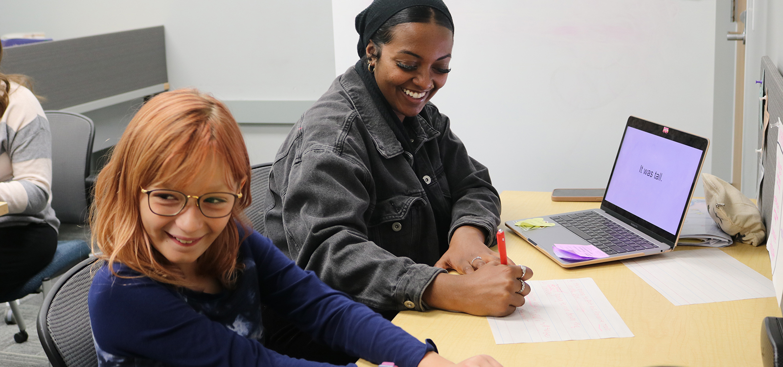 A Husker student and a young girl laugh during a tutoring session at the Schmoker Reading Center.