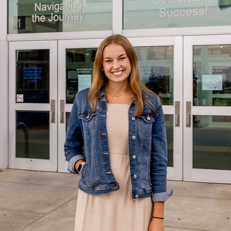 Student teacher outside high school entrance doors.