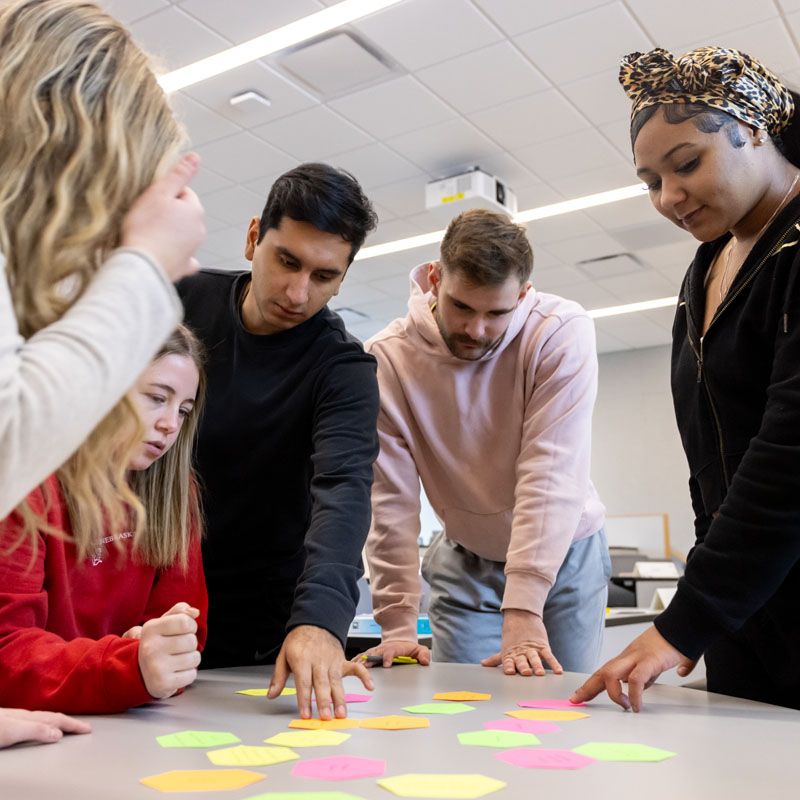 Group of people collaborating around a table with colorful sticky notes.