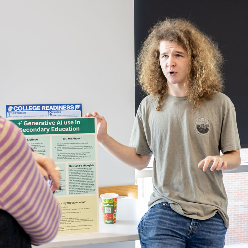 Person discussing a poster about generative AI in secondary education, in a casual setting.