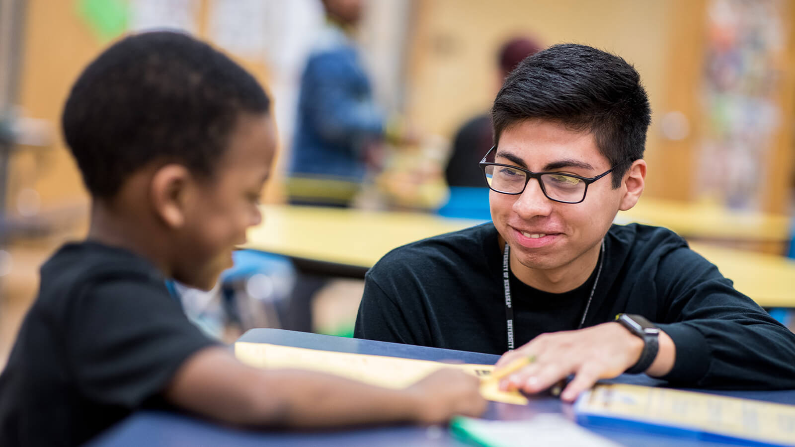 Student working with elementary student in classroom