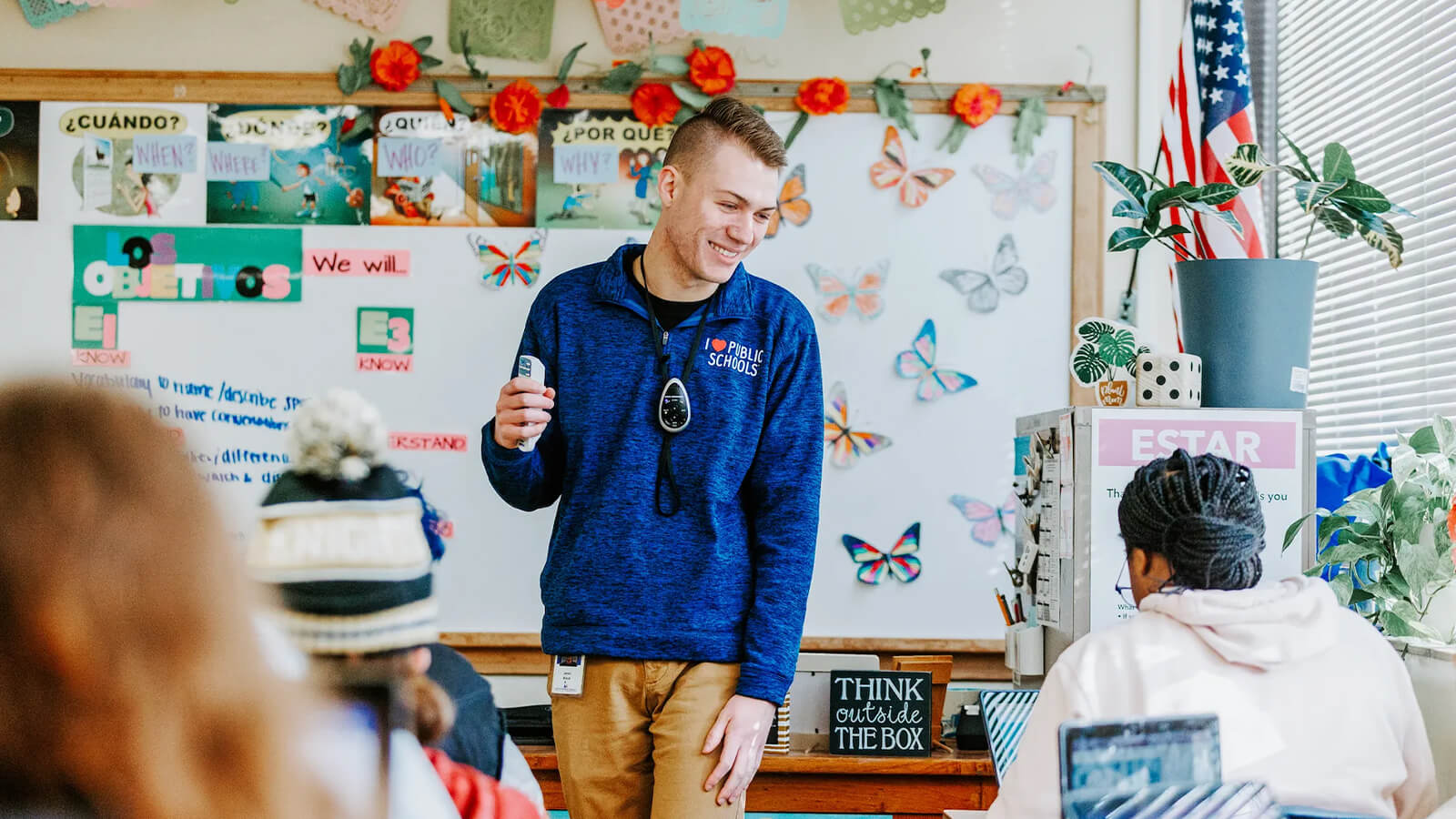 Student teacher in from of classroom, with whiteboard in background.