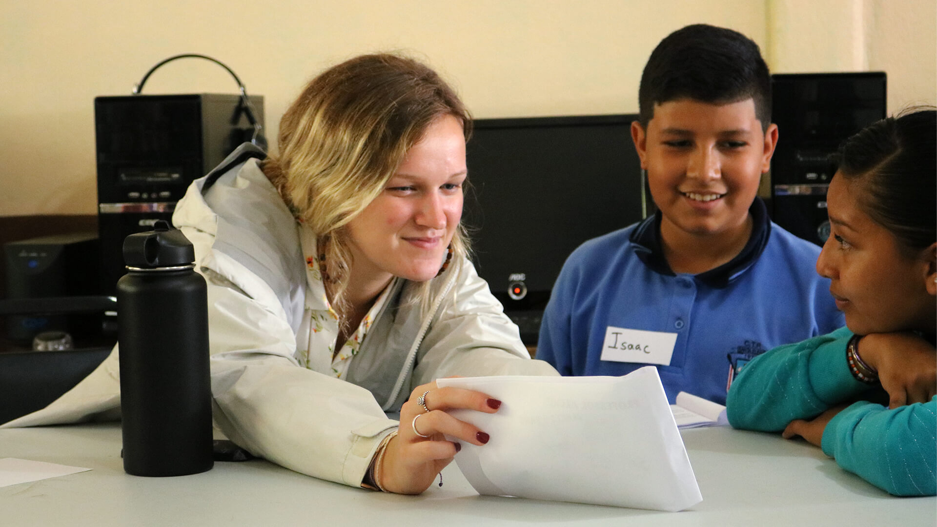 Student teacher works at a table with two students.