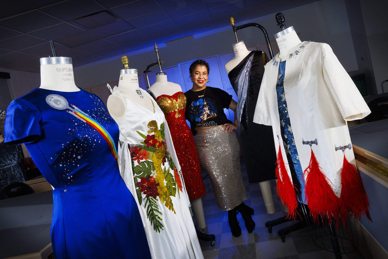 Woman posing with several dressed mannequins. 