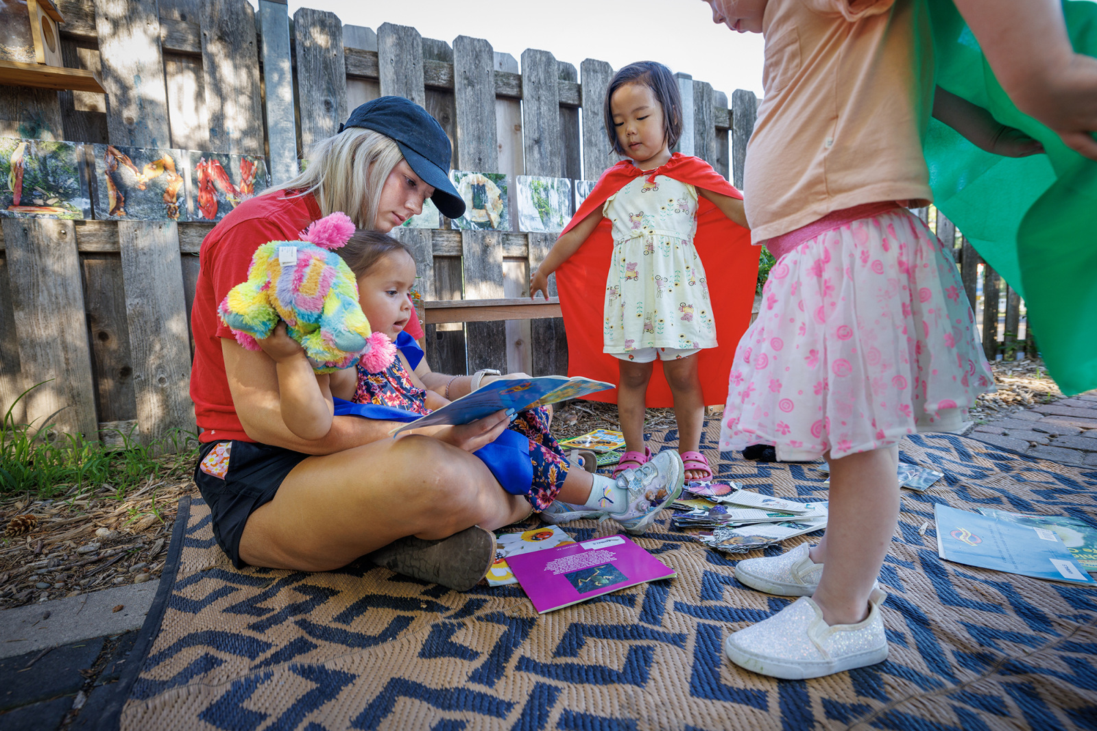 Woman reading to children in outdoor play space.