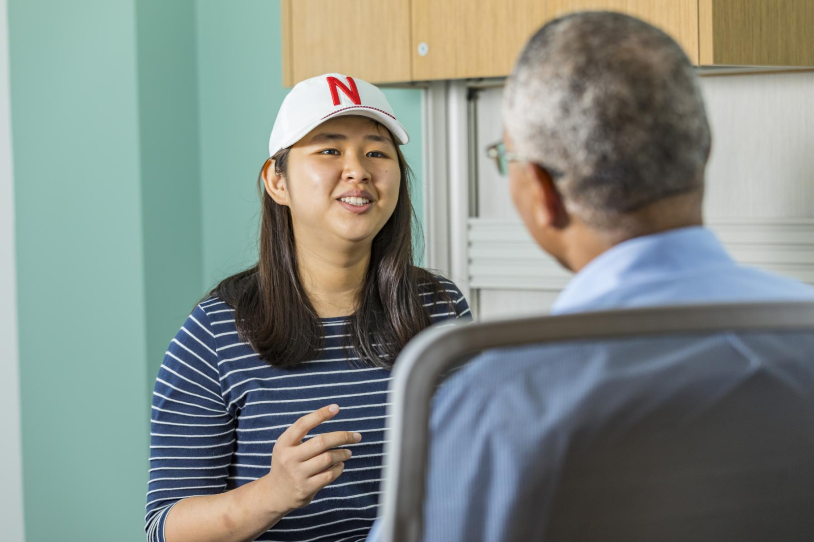 Young women in Nebraska hat talks with professor.