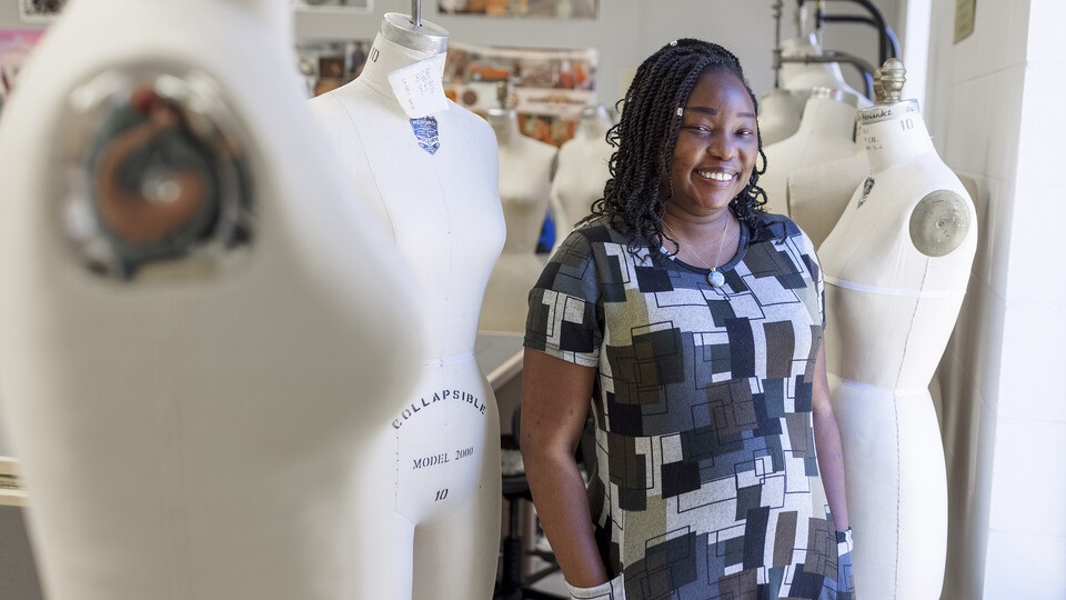 Woman standing by dress forms.