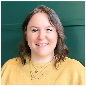 Person wearing a mustard yellow sweater and layered necklaces against a dark green background.