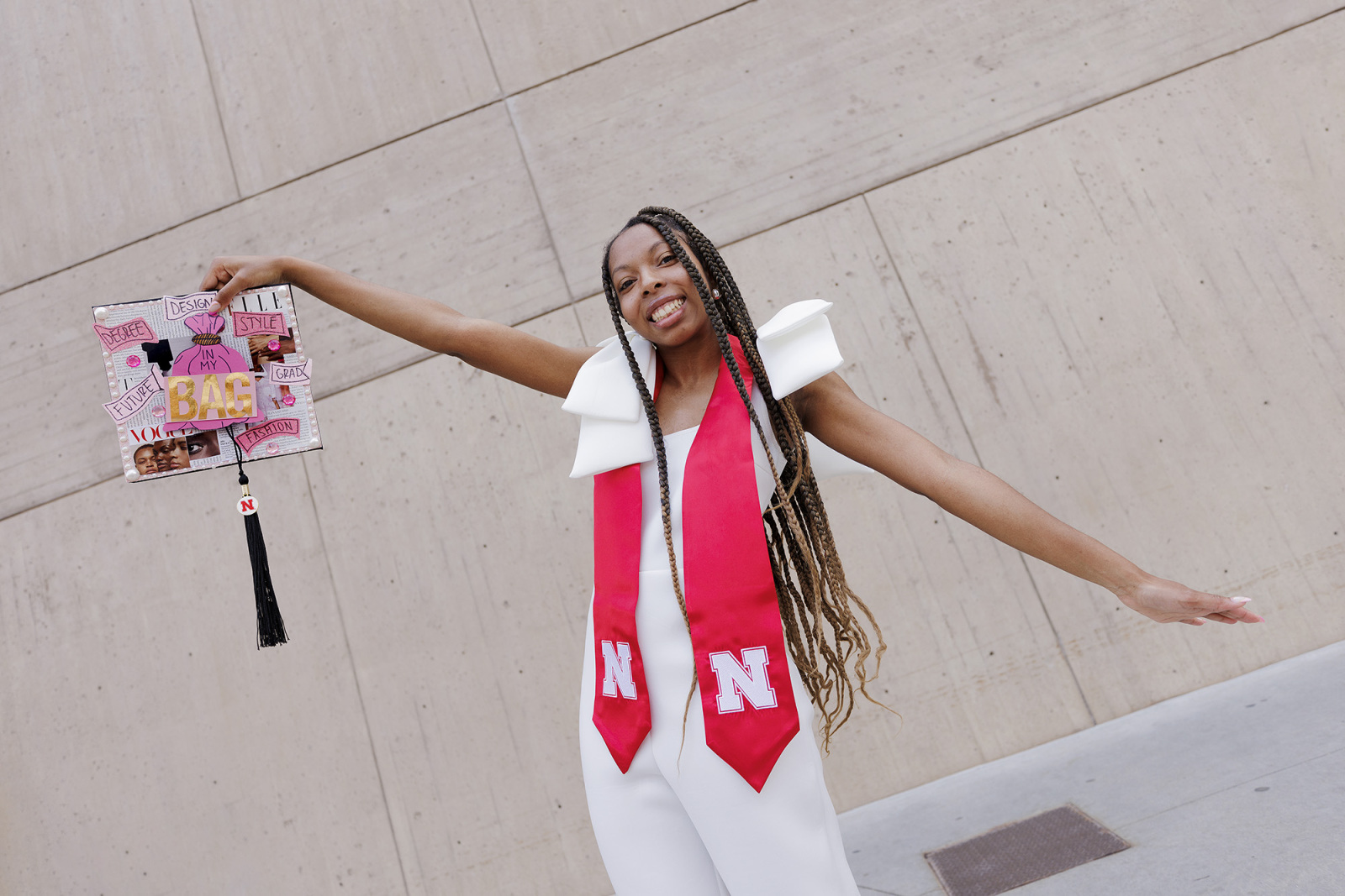 Woman with arms outstretched holding decorated graduation cap.