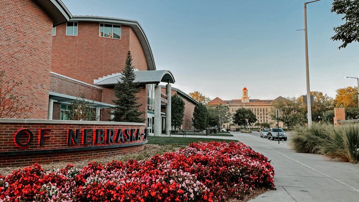 Red flowers in the landscaping in front of a large red brick building.