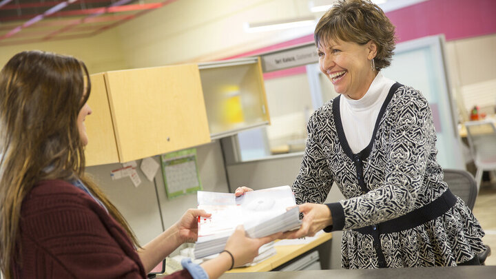 Teri Kaluza smiles as she hands a project off to a customer in the Pixel Lab. 