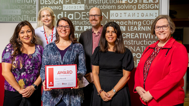 Six individuals posing for a photo, with one holding an award certificate.