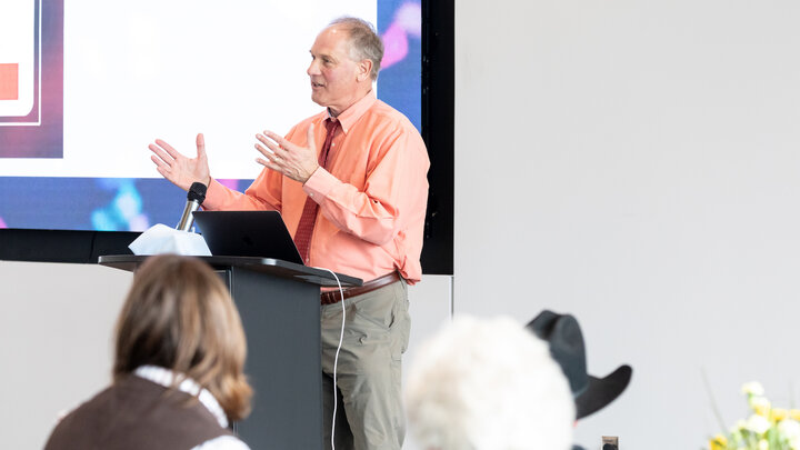 Ken Kiewra stands at the front of the room giving a lecture. 