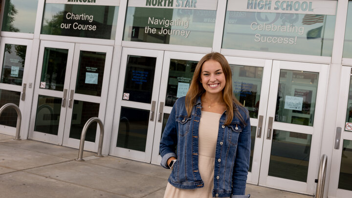 Sydney Gubbels stands outside of the glass door entrance to Lincoln North Star High School. 