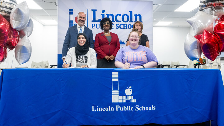 Dr. Paul Gausman (back row, left), Dr. Vann Price and Dr. Sue Kemp look on as two paraeducators sign their agreements to participate in the first cohort of the Para Pathway to Teaching pilot program.