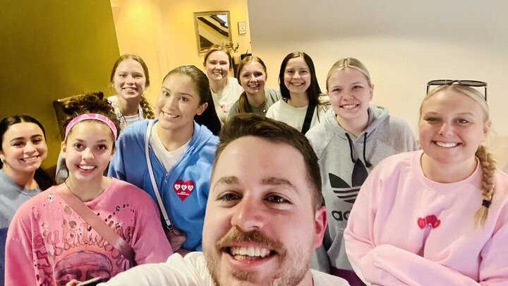 Ten individuals wearing casual clothing gather to take a selfie. 