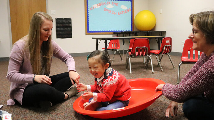 A Husker graduate clinician and her supervisor, Beth Dinneen, share in activities with a young girl with down syndrome during a speech therapy session at the Barkley Speech Language and Hearing Clinic.