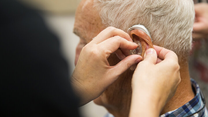 A gentleman is fitted with a hearing aid at the Barkley Speech Language and Hearing Clinic.