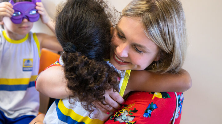 A female adult hugs a child at a nursery school in Brazil. 