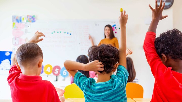 Students in a classroom raising their hands. 