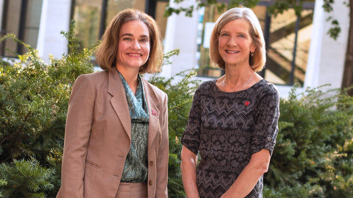 Two individuals standing in an outdoor setting, smiling for a photo. 