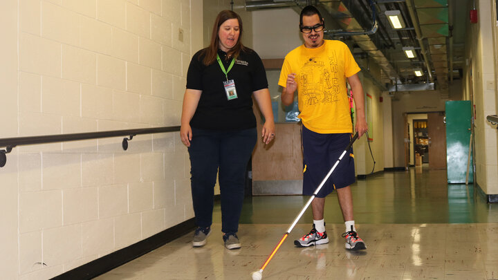 Sara Reuss guides a student at the Nebraska Center for the Education of Children Who Are Blind or Visually Impaired (NCECBVI) as an orientation and mobility specialist.