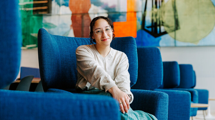 Monique Miller sits in a large blue chair and poses for a photo in Carolyn Pope Edwards Hall.