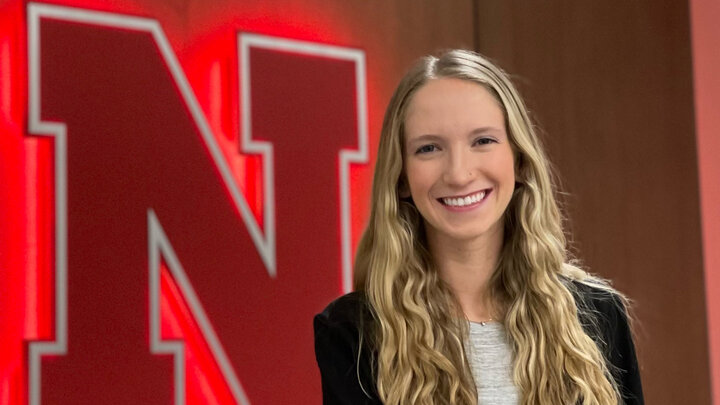 Nickie King headshot in front of large 'N' logo backlit by red lights