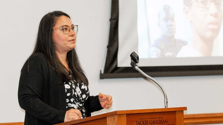 Deborah Rivas-Drake presents at a wooden podium in the Jackie Gaughn Multicultural Center. 