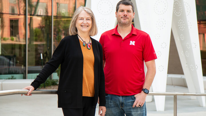 Beth Doll and Matt Cormley stand near a white sculpture outside Carolyn Pope Edwards Hall